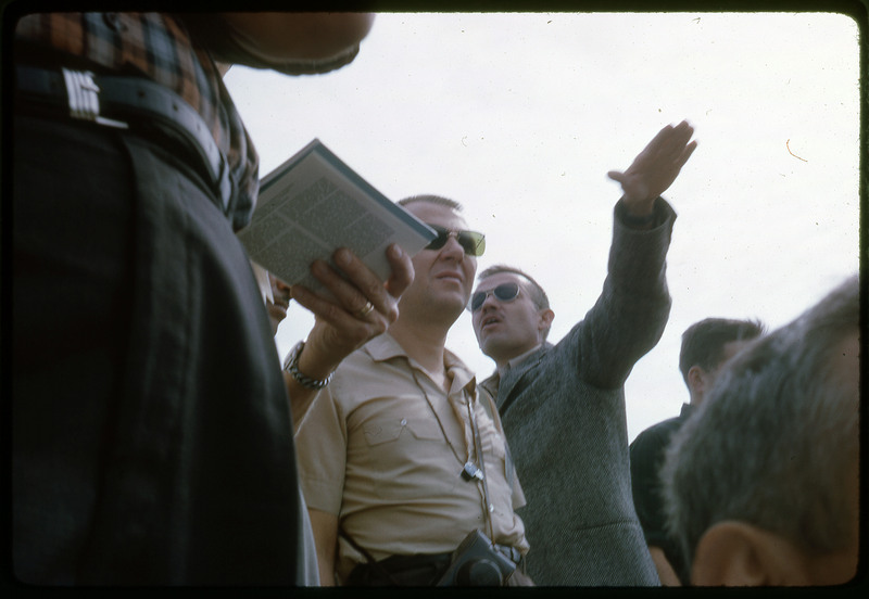 A photographic slide of a group of people gathered together from a low viewpoint.