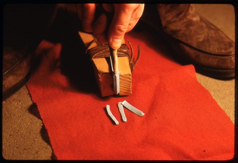 A photographic slide of someone operating a foot wedge to create a tool.