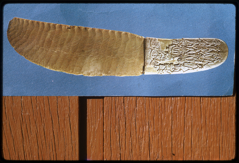 A photographic slide of an intricately carved lithic knife with a decorated handle.