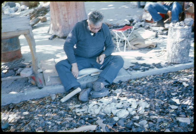 A photographic slide of a man flintknapping with antler tools.