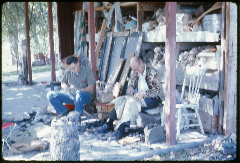 A photographic slide of a man, woman, and a young girl smiling in the front yard of a house.