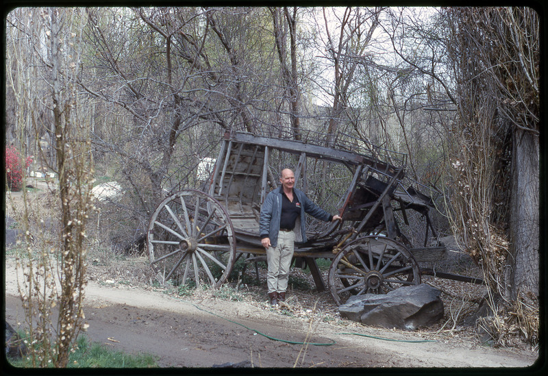 A photographic slide of Don E. Crabtree posing next to a dilapidated carriage.