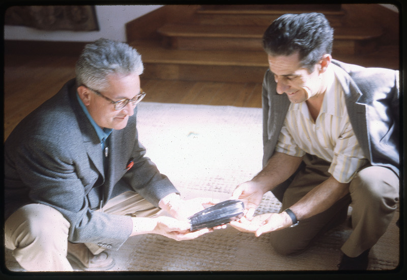 A photographic slide of two men holding an obsidian core.