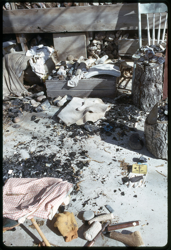 A photographic slide of a porch that has been converted into a flintknapping work station, covered in lithic debris and tools.