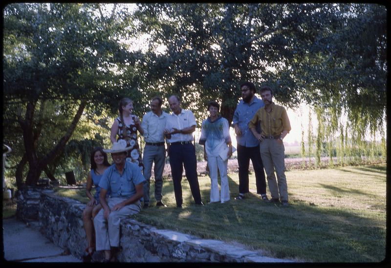 A photographic slide of a group of people smiling under the shade of treecover.