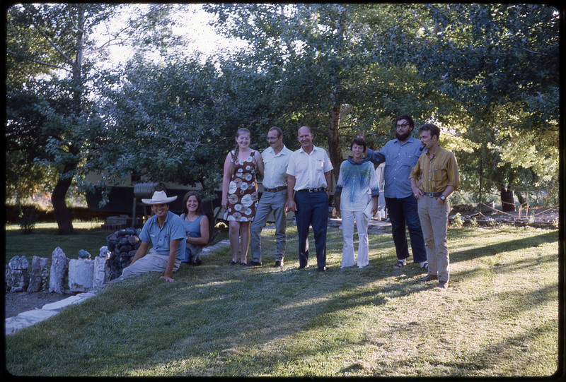 A photographic slide of a group of people smiling under the shade of treecover.