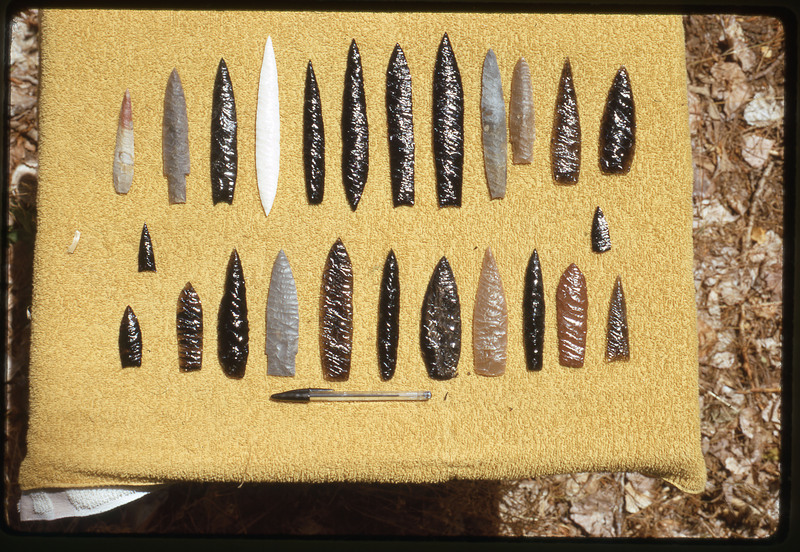 A photographic slide of a series of lithic points displayed on a yellow background.