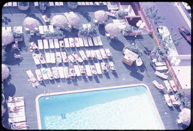 A photographic slide of an overhead view of a public pool and basking pool-goers.