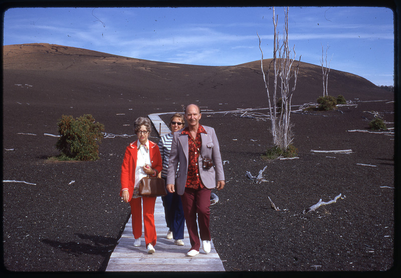 A photographic slide of Evelyn and Don E. Crabtree and another person posing in front of a dark sand flat.