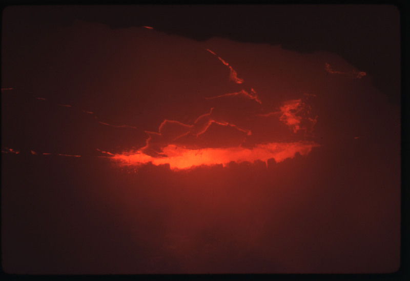 A photographic slide of the center of an active volcano, bubbling with lava and smoke.