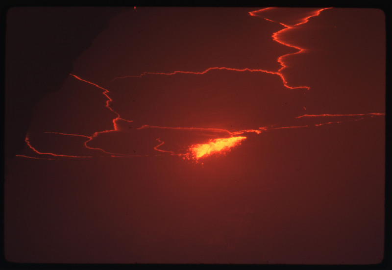 A photographic slide of the center of an active volcano, bubbling with lava and smoke.