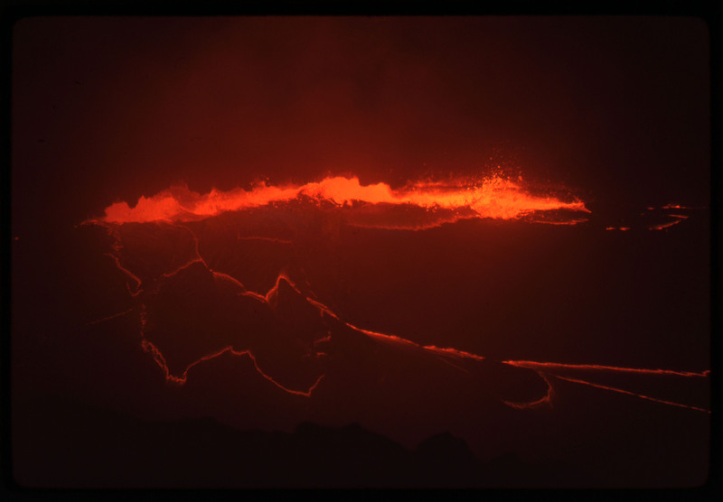 A photographic slide of the center of an active volcano, bubbling with lava and smoke.