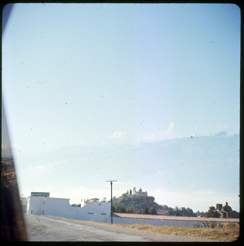 A photographic slide displaying an empty blue sky. There is a building and a powerline cut off by the frame.