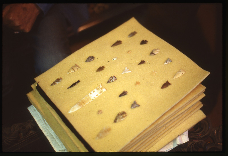 A photographic slide of an arrangement of flintknapped bifaces. They are neatly organized and uniquely flintknapped.