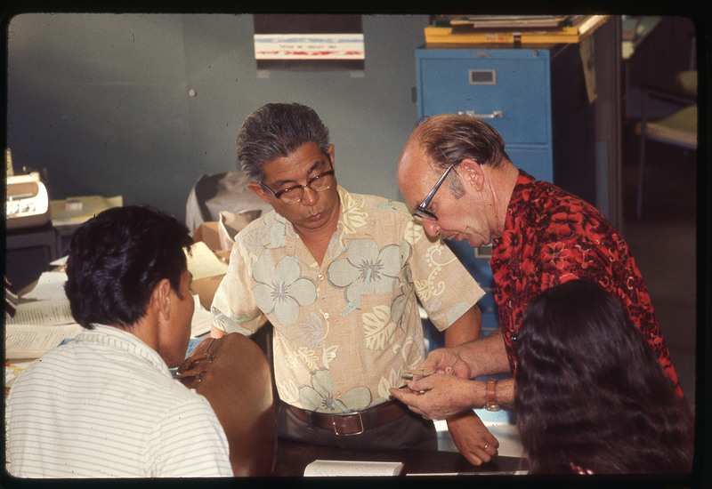 A photographic slide of Donald Crabtree and two colleagues analyzing lithic materials. They appear to be in an office.