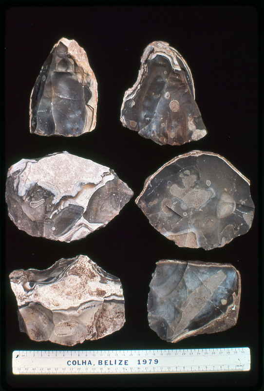 A photographic slide of lithic materials in an arrangement. There are six tools with unique rock coloring of brown and white. They appear to be flintknapped.