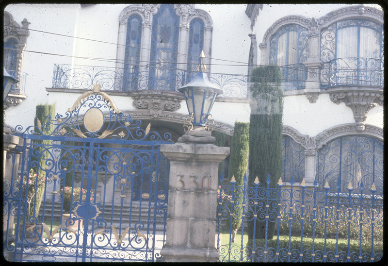 A photographic slide of a nice building with a blue fence and blue balcony. The building is labeled 330 and there is a manicured yard.