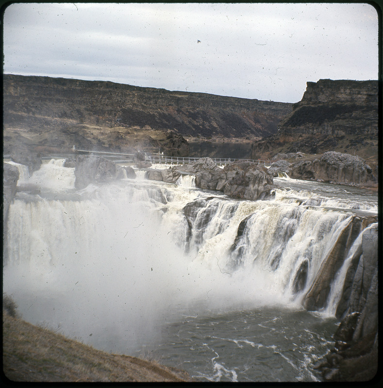 A photographic slide of a large waterfall. There is a large rocky canyon in the background and a river.