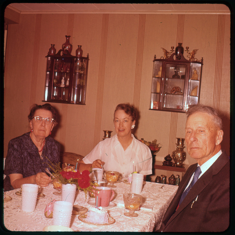 A photographic slide of a Evelyn Crabtree and two others sitting a table together eating cake.