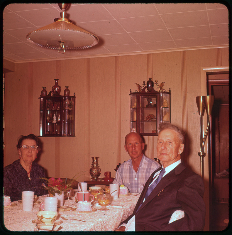 A photographic slide of Donald Crabtree and two others sitting together at a table.