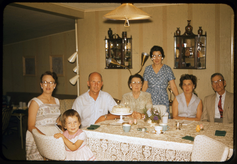 A photographic slide of seven people sitting together at a dinner table celebrating Donald Crabtree's birthday. Evelyn and Donald Crabtree are pictured.