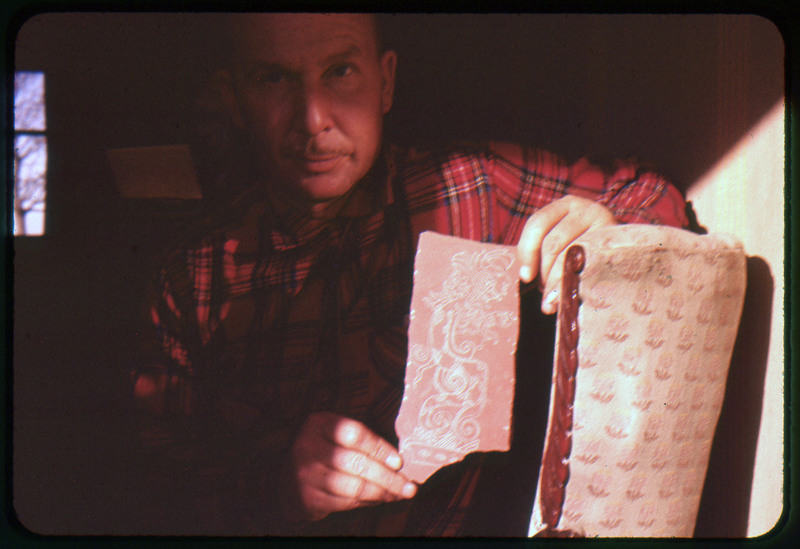 A photographic slide of Donald Crabtree holding what looks like an artifact with a detailed painting on it.