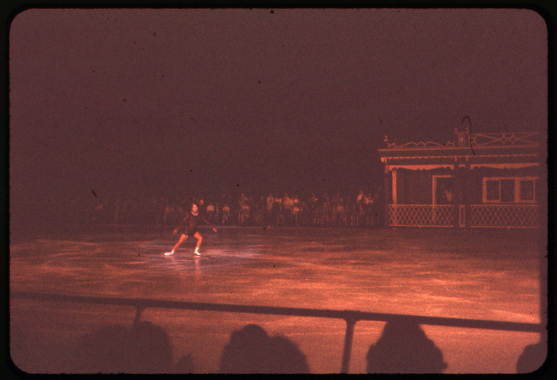 A photographic slide of a person figure skating in front of a large crowd.