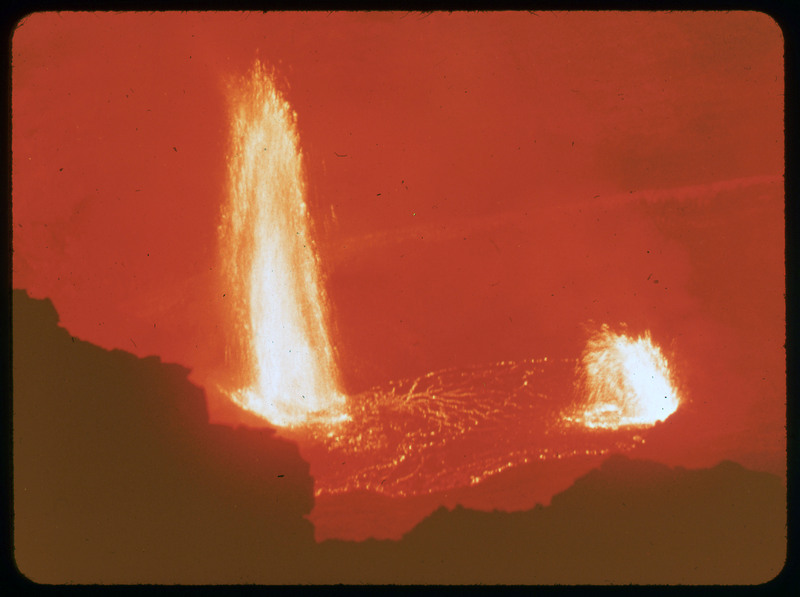 A photographic slide of lava spewing into the air from a large pool of molten lava.