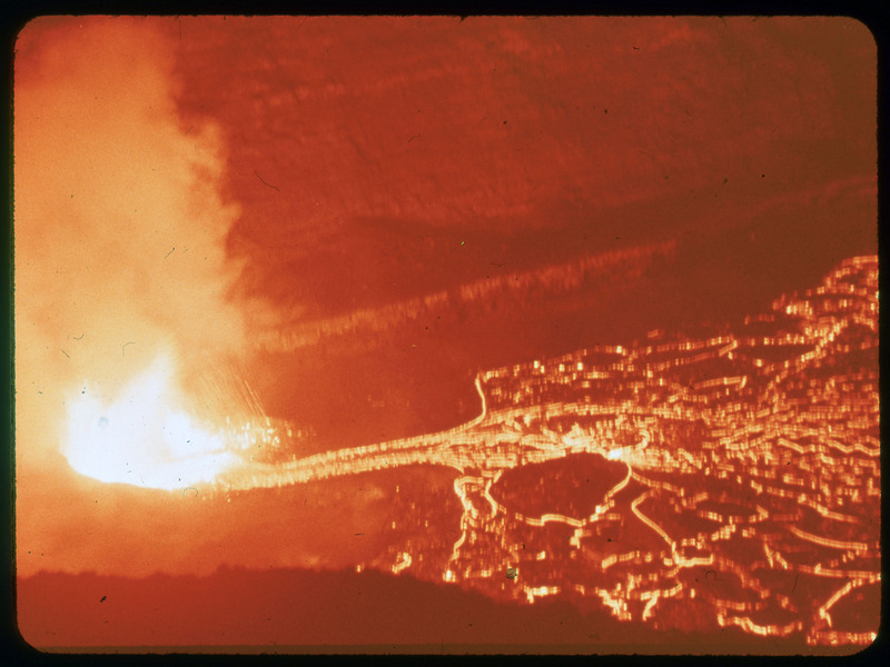 A photographic slide of a large magma pool with lava spewing into the air.