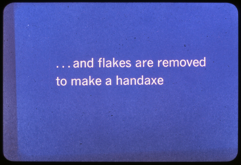 A photographic slide of a blue slide stating, "... and flakes are removed to make a handaxe."