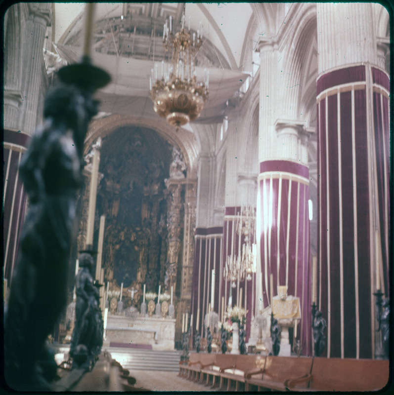 A photographic slide of the inside of a cathedral. The photo is somewhat blurry. There are some statues visible and some religious items in the room.