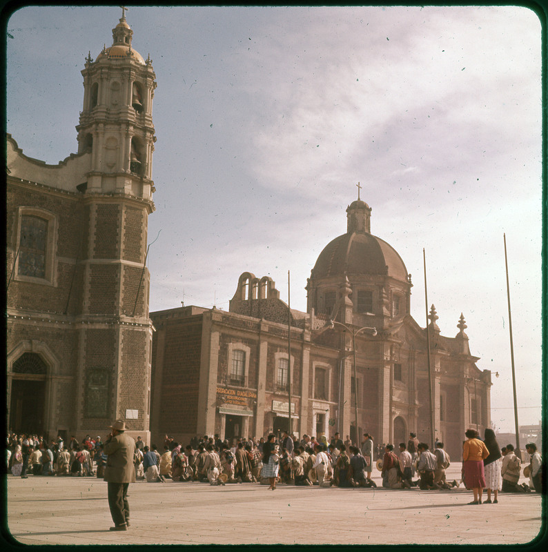 A photographic slide of the Basilica of Our Lady of Guadalupe building. There are many people outside the building.