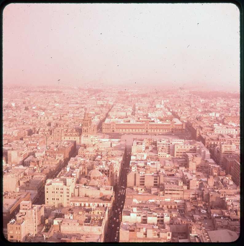 A photographic slide of an aerial view of a city. There are many buildings and a haze.