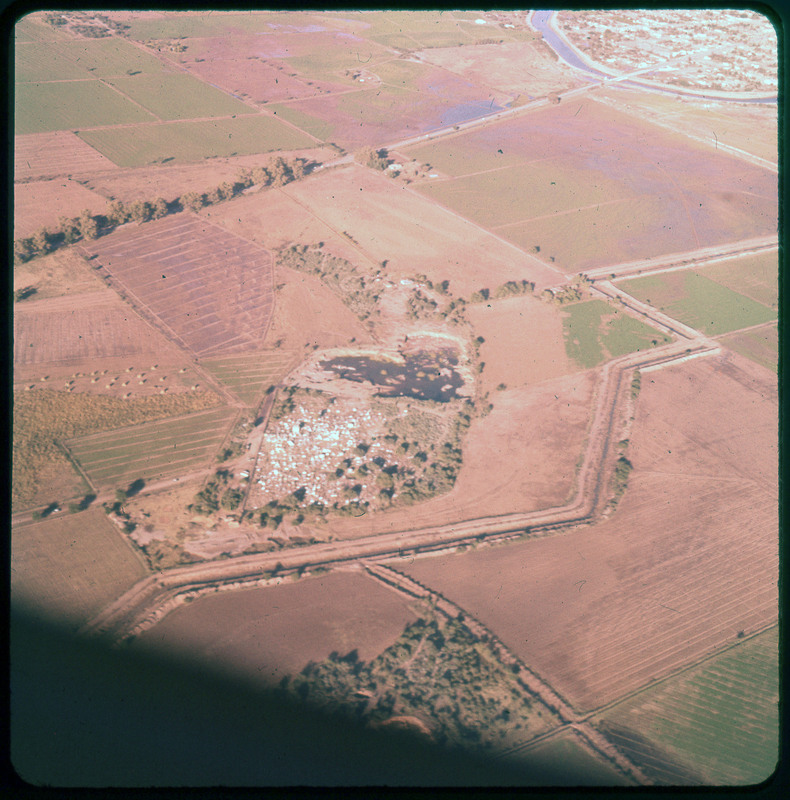 A photographic slide of agricultural fields and a road. In the center of the photo, there is what resembles a rock pit.