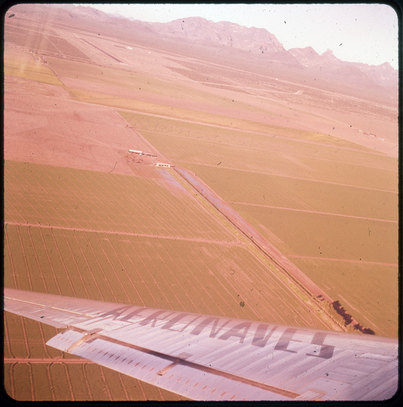 A photographic slide of agricultural fields from an aerial view. There are some structures visible.