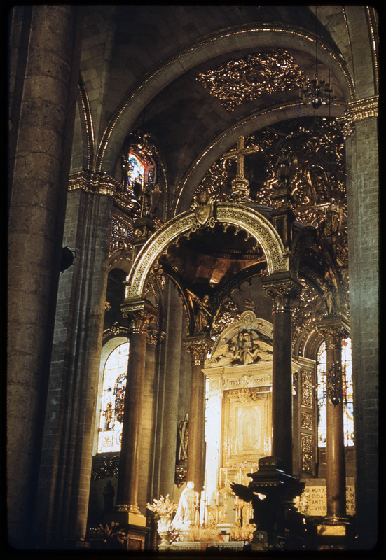 A photographic slide of a religious altar. It is gold in color with a cross and looks to be inside of a church.