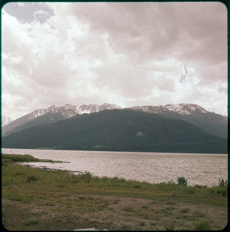 A photographic slide of snowy mountains in the background and a large lake in the foreground.