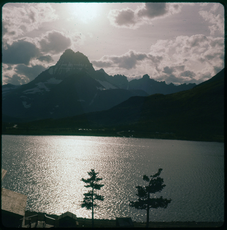 A photographic slide of a large lake with mountains in the background. The photo is slightly blurry.