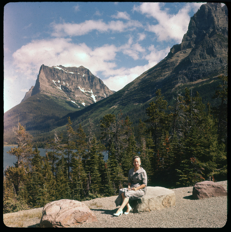 A photographic slide of a large mountain lodge. There is a large lawn in front and trees. The sky is cloudy.