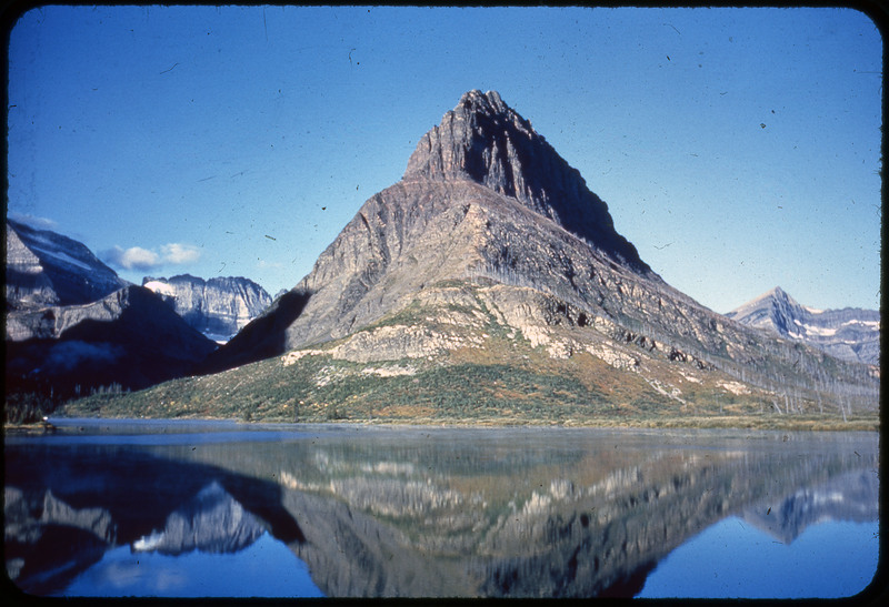 A photographic slide of a river corridor surrounded by many rocks. There are some trees and the river is rushing.