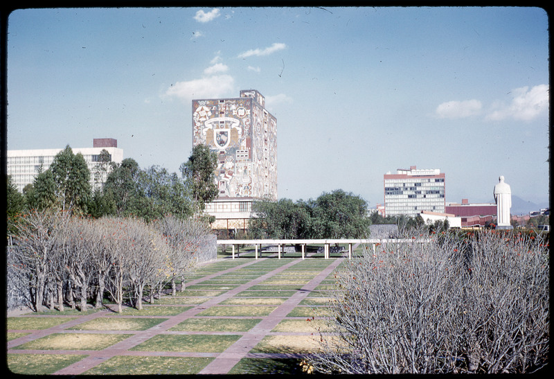 A photographic slide of a grassy campus of a large building decorated with historical art.