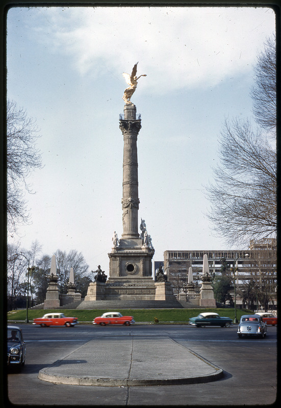 A photographic slide of a monument depecting a golden statue of an angel sitting atop an ornately carved column.