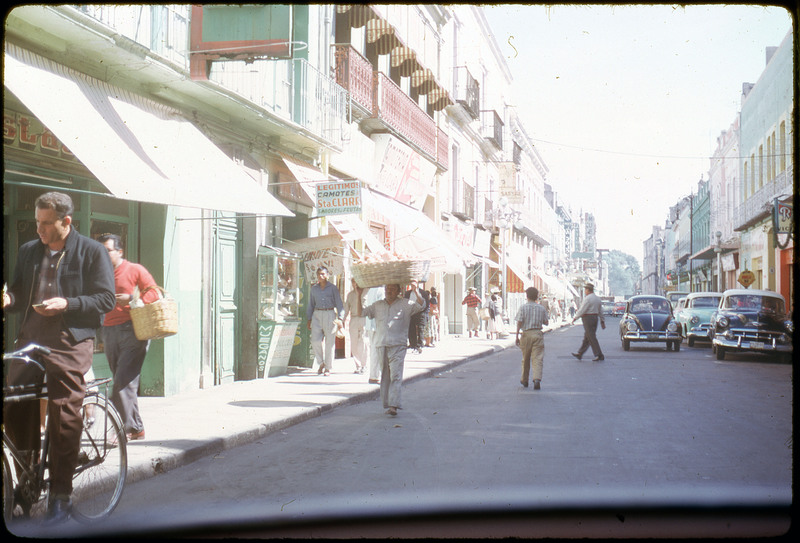 A photographic slide of people walking on a city sidewalk and cars parked on the side. This seems to be the same photo as CE_B81_F5-Item9.