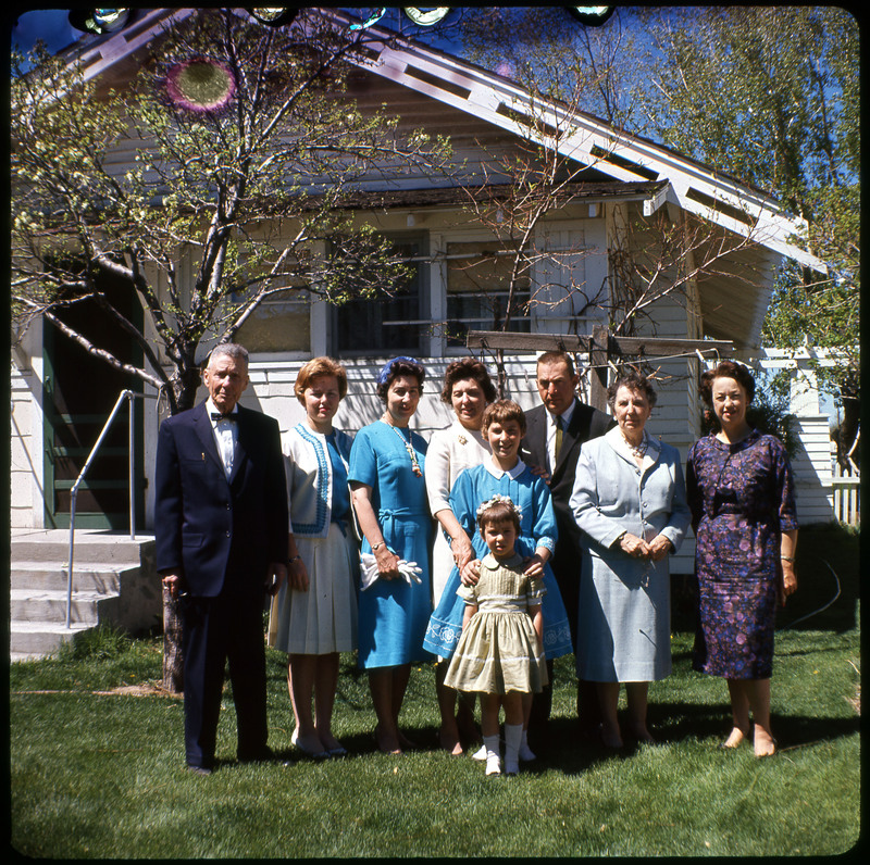 A photographic slide of Evelyn Crabtree and assumingly her family. They are dressed nice and standing outside of a house.