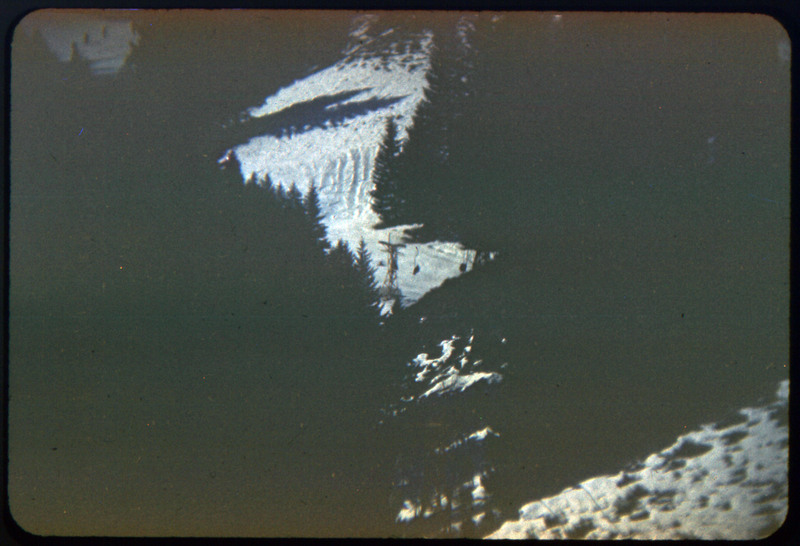 A photographic slide of a snowy mountain range. There is a chairlift slightly visible.