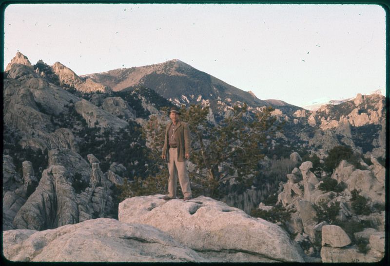 A photographic slide of Donald Crabtree standing on a rock in front of a giant valley of trees and rocks.