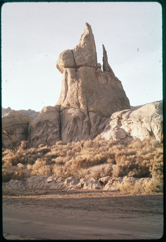 A photographic slide of a rock formation with standalone features and a grassy base.