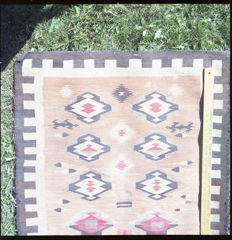 An image of a woven blankets created by an unknown creator. One blanket is laid out with a portion of item visible with yard stick to indicate size.