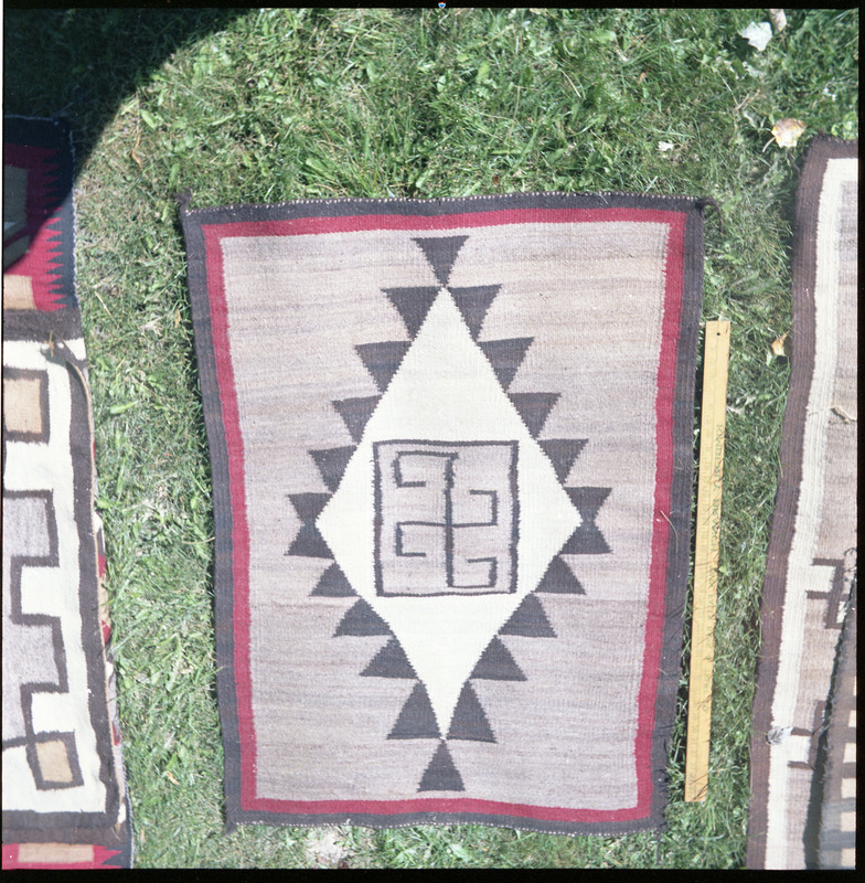 An image of a woven blankets created by an unknown creator. One blanket is laid out with yard stick to indicate size.