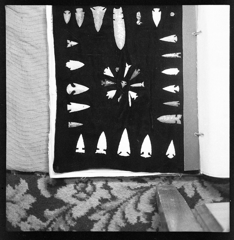 A black and white negative of eccentric stone tool items. There are different bifaces arranged neatly on black pages. They are all unique, detailed, and of different stone materials.
